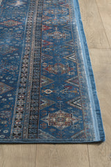 The Bohemian Tracery Rug - Blue - 2221B displays intricate geometric and floral patterns with red, brown, and cream accents atop a light wood floor, featuring multiple borders and detailed motifs.