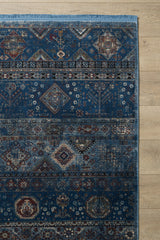 The Bohemian Tracery Rug - Blue - 2221B showcases intricate navy, cream, and burgundy geometric and floral patterns in elegant horizontal bands, making a striking statement on a light wood floor.
