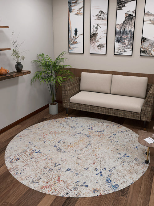 Load image 1 in gallery view. A cozy room featuring the Boho Babe - Washable Rug - JR1664 (Custom Size) in cream and beige on a wooden floor, a wicker sofa with beige cushions, art, shelves with decor, plants, and a small table—ideal for high-traffic areas.