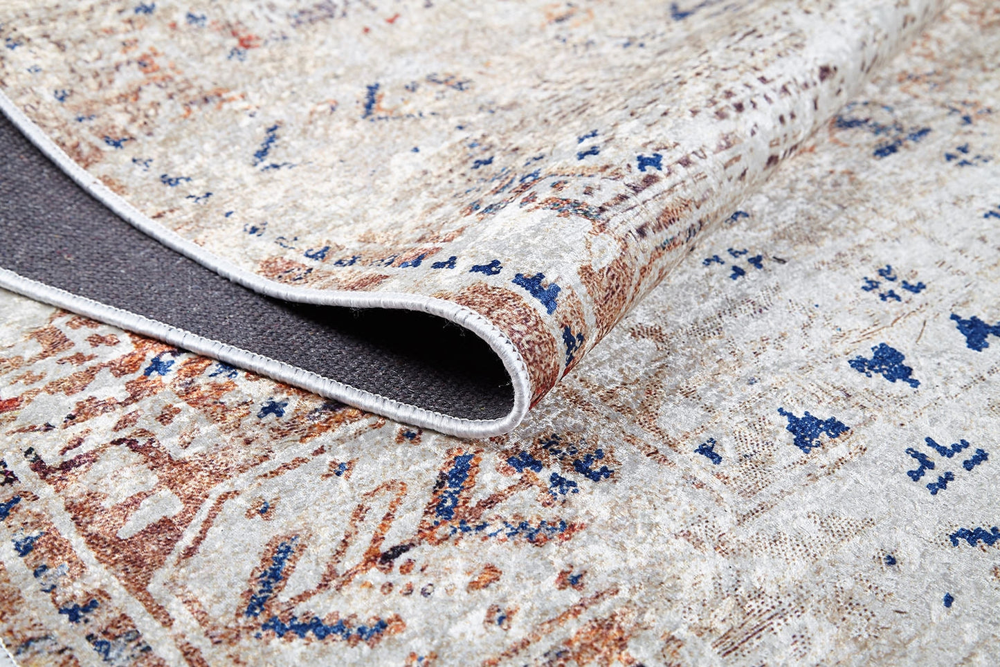 A close-up of the Boho Babe - Washable Rug - JR1664 (Custom Size) displays folded edges and an intricate beige, blue, and brown design on textured fabric—ideal for high-traffic areas and easy to clean.