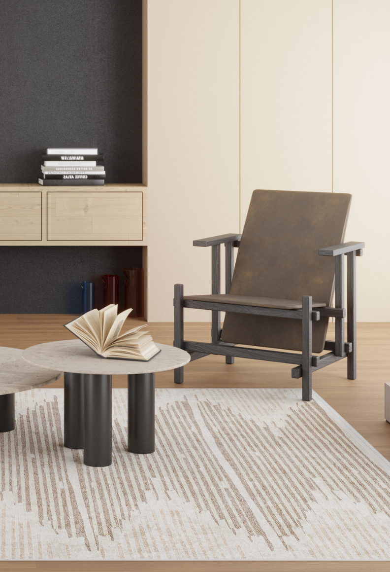 A modern living room with a brown accent chair, a round coffee table holding an open book, the Boho Paradise - Washable Rug - JR2004 in cream and beige tones, and built-in shelves with stacked books in the background.