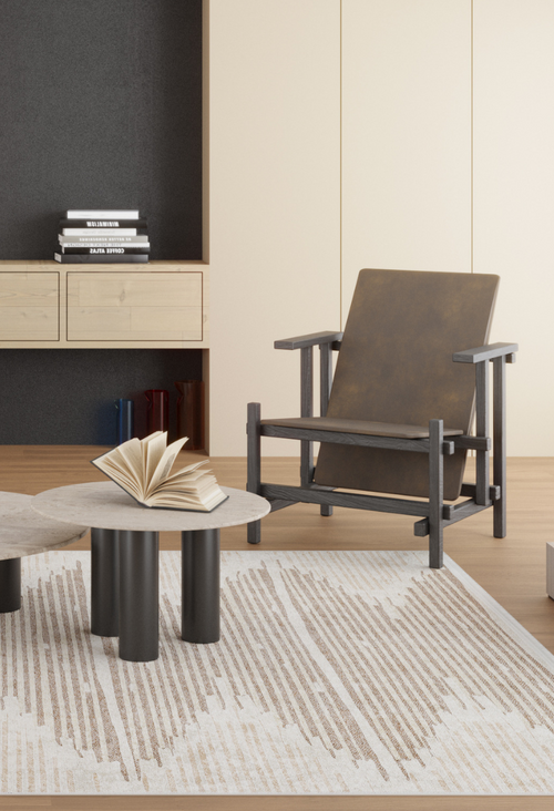 Load image 1 in gallery view. A modern living room with a brown accent chair, a round coffee table holding an open book, the Boho Paradise - Washable Rug - JR2004 in cream and beige tones, and built-in shelves with stacked books in the background.