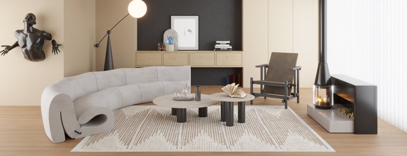 Modern living room with a curved light gray sofa, two round coffee tables, a black armchair, wall art, and a fireplace. The sculptural décor and the Boho Paradise - Washable Rug - JR2004 add artistic style to the minimalist space.
