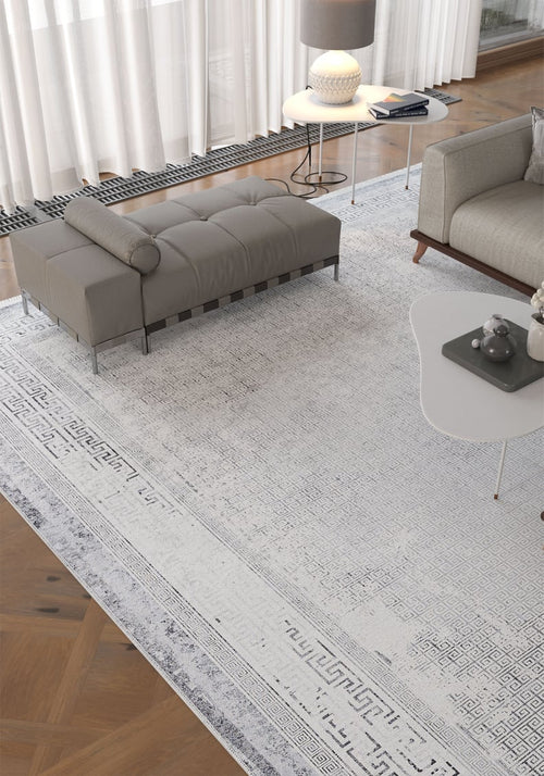 Load image 1 in gallery view. Modern living room with the Bold Borderline - Washable Rug - JR1984, ideal for high-traffic areas, a gray upholstered bench, white coffee table with decor, gray sofa, lamp on a side table, parquet wood floors, and large windows with sheer curtains.
