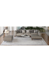 A modern living room with a gray sectional, ottoman, and two coffee tables features the Bold Borderline - Washable Rug - JR1984 (Custom Size), ideal for high-traffic areas, beneath. Decorative items and plants sit by large windows with sheer curtains.