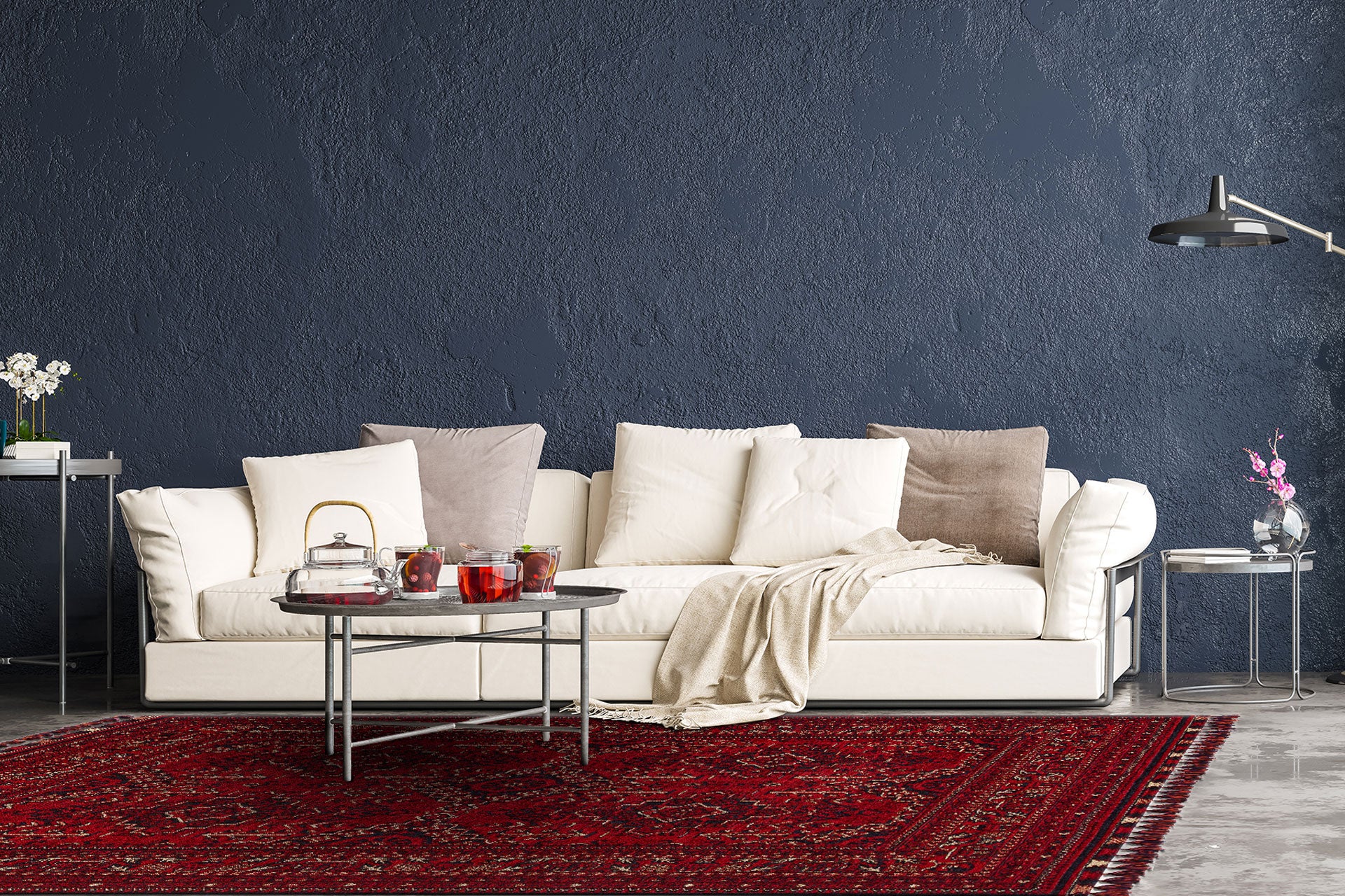 A modern living room with a white sofa, neutral cushions, and a beige throw sits against a dark blue wall. The floor features the Bold Thread - Kilim - BHR05 rug in Turkish design beneath a round coffee table with tea and glassware.