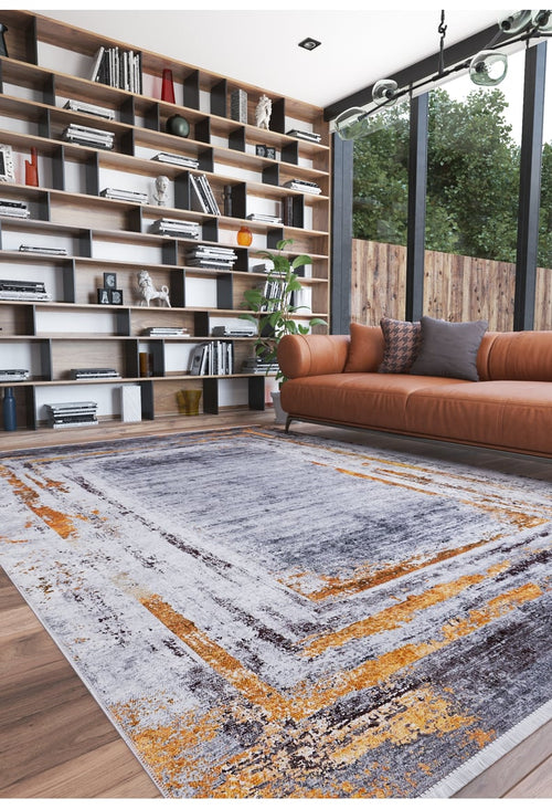 Load image 1 in gallery view. A modern living room with a large window, leather sofa, and the Bold and Chic - Washable Rug - JR1198 in gray, orange, and white—an allergy-friendly choice. Floor-to-ceiling shelves hold books and decor; trees are visible outside.