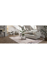 A cozy attic living room features a white sofa, neutral pillows, modern glass coffee table, potted plants, and the Bold and Geometric - Washable Rug - JR1410 on wood floors—ideal for high-traffic areas beneath slanted exposed-beam ceilings.