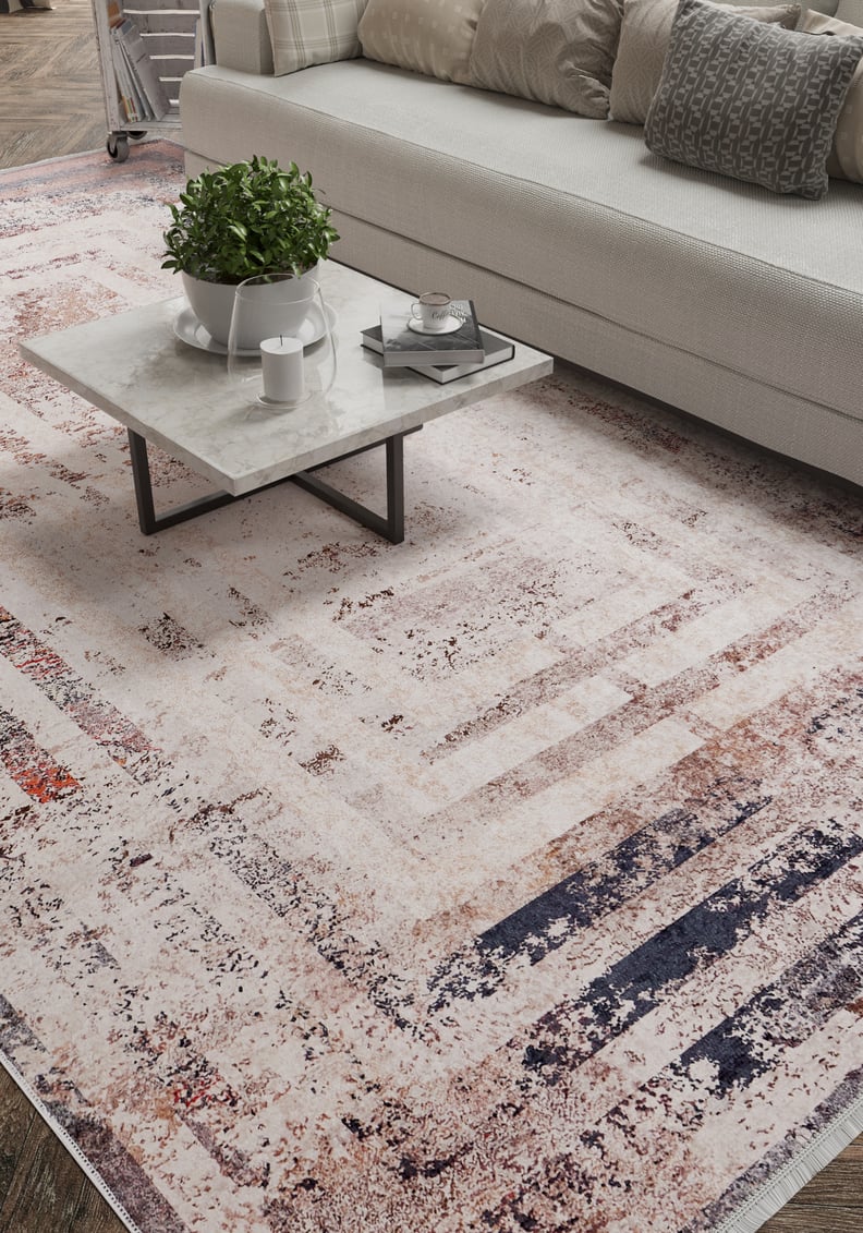 A modern living room features a light gray sofa, patterned cushions, and a marble coffee table on the Bold and Geometric - Washable Rug - JR1410 (Custom Size), perfect for high-traffic areas and complementing textured, geometric decor.