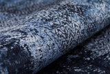 Close-up of the Bold and Minimalist - Washable Rug - JR1229 (Custom Size), featuring a textured, rolled-up surface with a mottled blue, grey, and black pattern—perfect for high-traffic areas and modern decor.