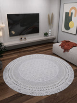 A modern living room featuring the Borderline Brilliance - Washable Rug - JR1987 (Custom Size) in gray-anthracite, ideal for high-traffic areas, with wooden floors, a wall-mounted TV, minimalist decor, and abstract wall art.