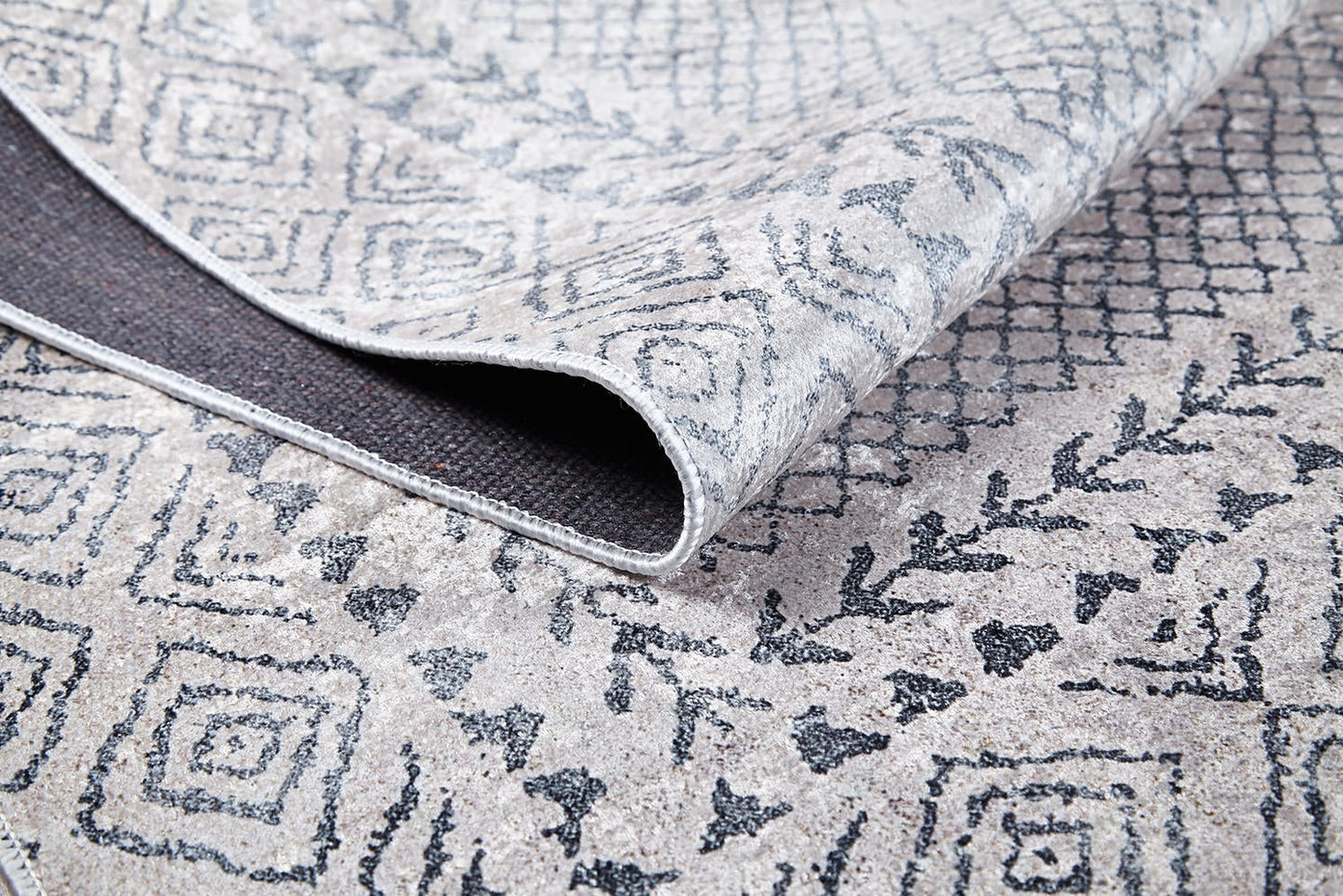 A close-up of the Borderline Brilliance - Washable Rug - JR1987 (Custom Size) in gray-anthracite, featuring geometric and diamond patterns with a dark backing—perfect for high-traffic areas.