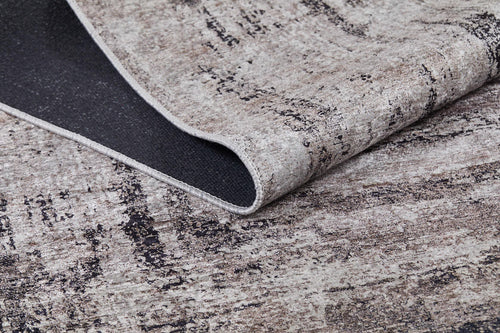 Load image 1 in gallery view. A close-up of the Borderline Chic - Washable Rug - JR1156 (Custom Size), featuring a modern, neutral abstract pattern. One corner is lifted to reveal its dark, textured underside—perfect for allergy-sensitive homes seeking bronze and brown tones.