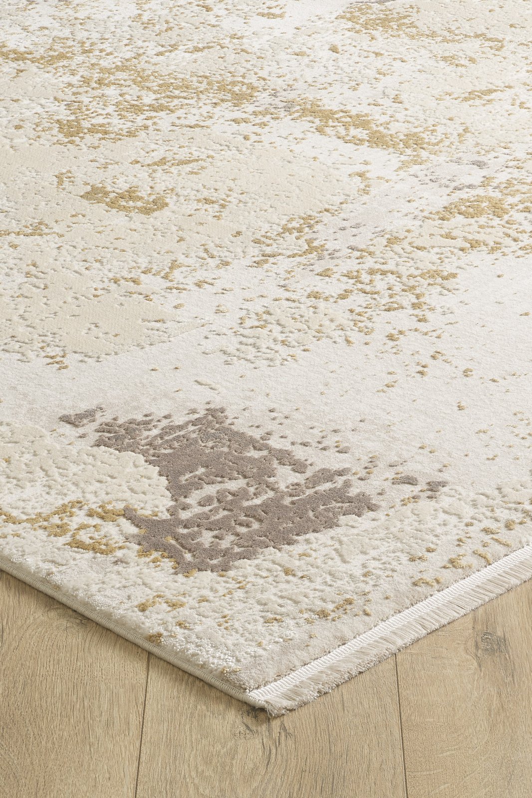 A close-up of the Bright Swirls Contemporary Rug - M657F displays its abstract beige, cream, and light brown pattern on a light wood floor, highlighting the modern rug’s edge and textured surface.