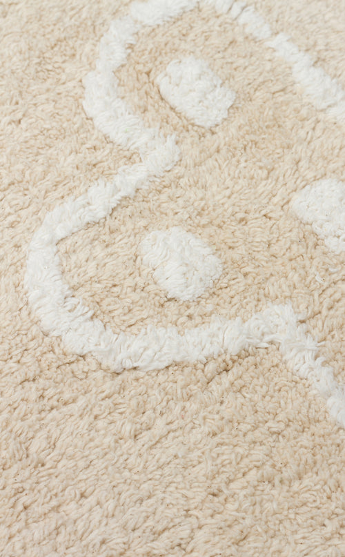 Load image 1 in gallery view. A close-up of the Calm Nest - Washable Shaggy - CBN16 rug in cream beige, featuring ultra-soft, fluffy fibers and a white abstract curved pattern.