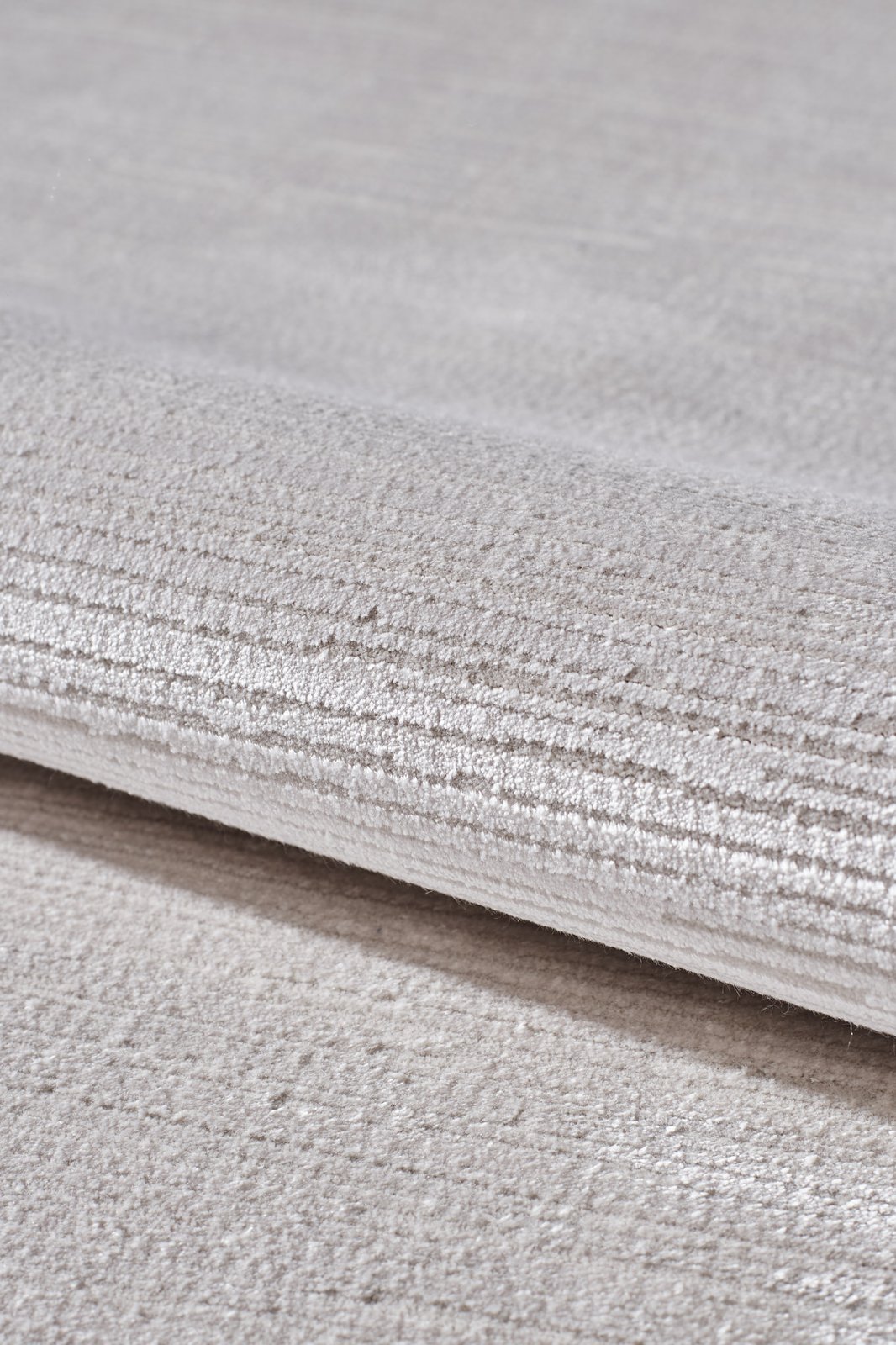 A close-up of the Candlelight Comfort Modern Ivory Rug - EW2824 showcases its soft, textured surface with subtle horizontal lines—an elegant neutral beige rug ideal for enhancing any room’s decor.