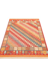 The Canyon Shade - Kilim - NMD11 is a vibrant polyester rug with bold diagonal zigzag lines and Greek key motifs in red, orange, blue, and beige. Its border has repeating geometric shapes, making it perfect for modern interiors. Shown flat.