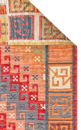A close-up of the Canyon Shade - Kilim - NMD11 rug corner, folded over. This vibrant piece displays geometric patterns in red, blue, orange, cream, and yellow—ideal for adding textured detail to contemporary interiors.