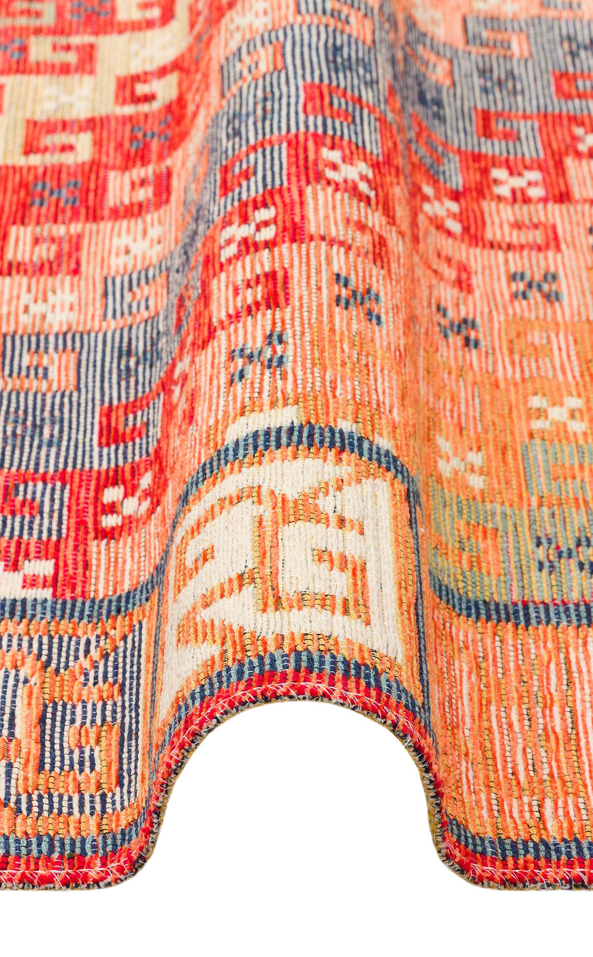 A close-up of the Canyon Shade - Kilim - NMD11 rug, featuring vibrant geometric patterns in red, orange, blue, and cream with a wavy fold along the edge—ideal for modern spaces—set against a white background.