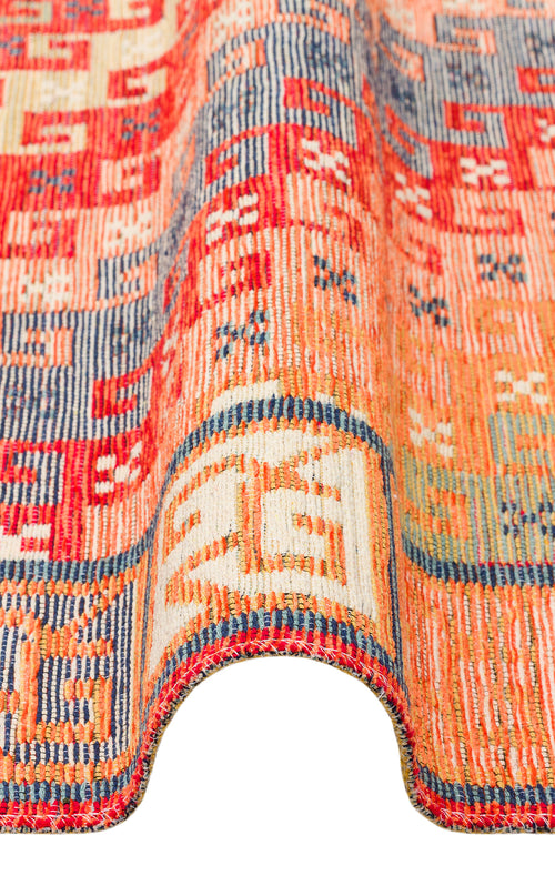 Bild 1 in Galerieansicht laden. A close-up of the Canyon Shade - Washable Reversible Kilim - NMD11 showcases its vibrant red, orange, blue, and cream geometric patterns, elegantly draped in a wavy curve against a white background.