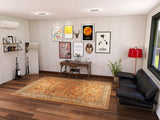 A modern living room featuring the Celestial Vintage - Washable Rug - JRN1020, a black sofa, wooden desk, wall art, red floor lamp, guitar, bookshelf, potted plant, and a large window streaming in natural light.