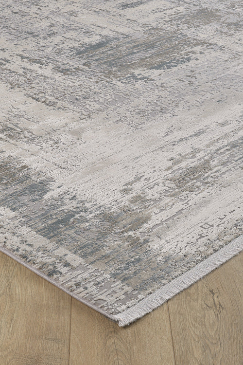 Load image 1 in gallery view. A close-up of the ChromaBurst Premium Rug - Bright - MT177, a machine-made acrylic-viscose rug with an abstract gray, cream, and blue pattern, textured surface, short fringe, and shown on a light wood floor.