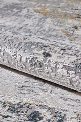 A close-up of the ChromaBurst Premium Rug - Dark - MT175 shows its textured, machine-made surface with light gray, beige, dark blue, and gold in an abstract pattern for a stylish yet durable finish.