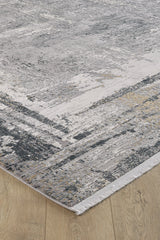 Close-up of the ChromaBurst Premium Rug - Dark - MT175, featuring an abstract gray, white, and beige pattern with short fringe on the edge, lying on a light wood floor. This modern rug is machine-made.
