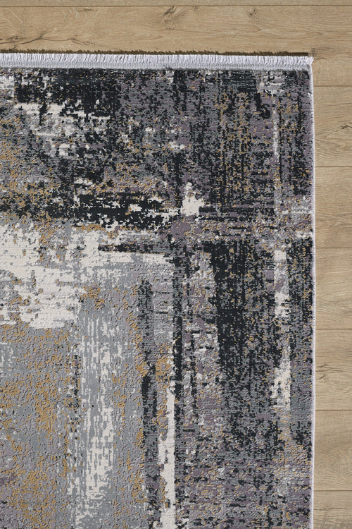 Load image 1 in gallery view. A close-up of the ChromaBurst Premium Rug - Dark - MT175 shows its modern abstract pattern in gray, black, beige, and white shades with fringe along the upper edge, resting on a light wooden floor.