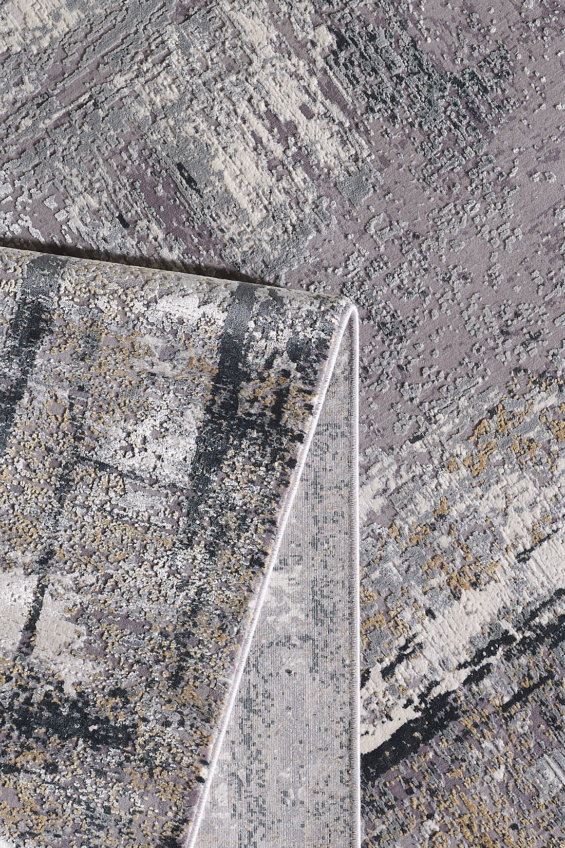 A close-up of the ChromaBurst Premium Rug - Dark - MT175 showcases abstract grey, beige, and black patterns. The flipped corner reveals its plush acrylic-viscose thickness and detailed machine-made underside.