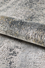 A close-up of the Chromatic Flair Contemporary Rug - Charcoal (M660A) shows an abstract, textured pattern in gray, beige, and cream with distressed detailing and raised areas for a multidimensional look.