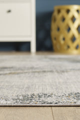 A close-up of the Chromatic Flair Contemporary Rug - Charcoal - M660A on a wooden floor, with a white cabinet and a decorative gold stool softly blurred in the background.