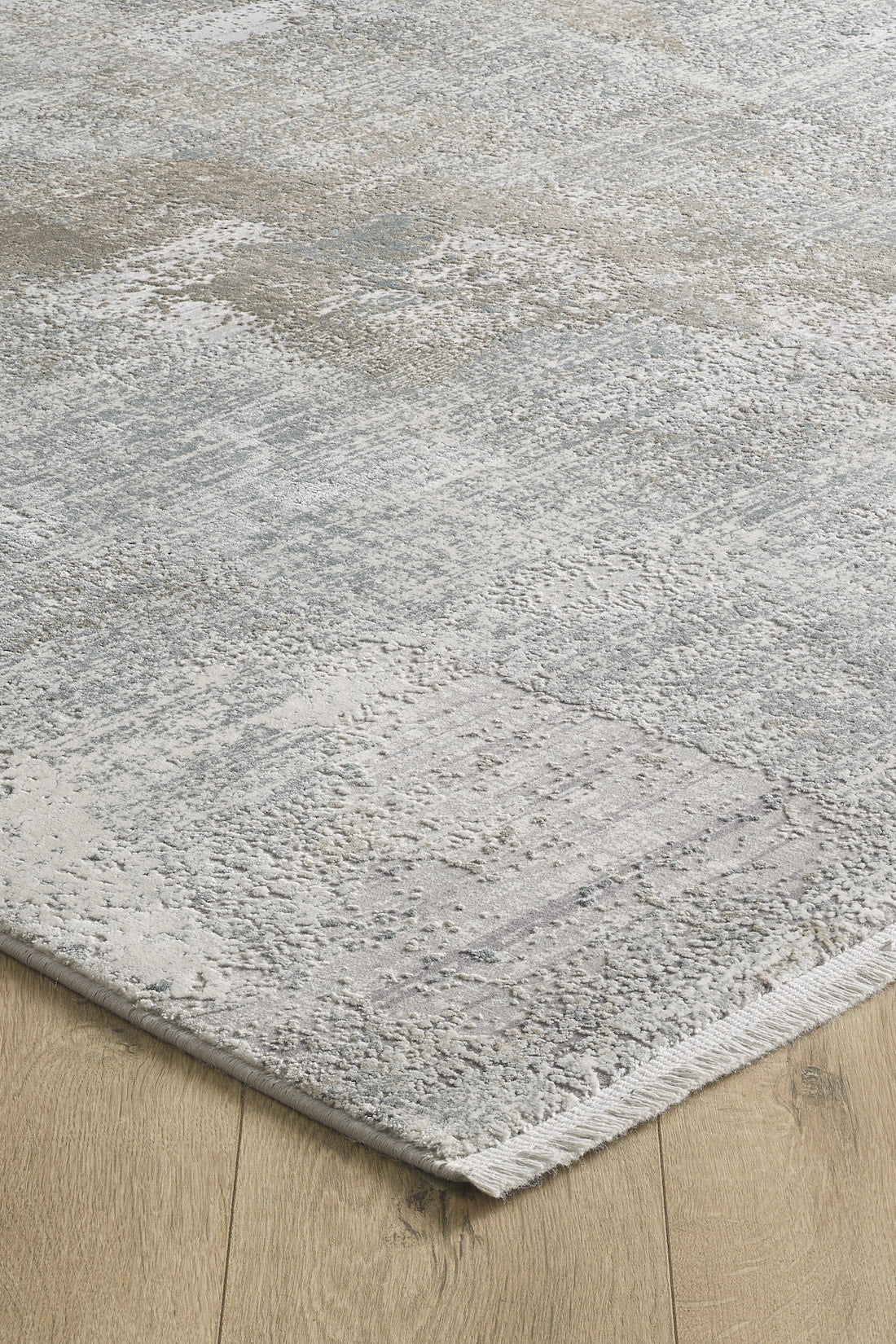 A close-up of the Chromatic Flair Contemporary Rug - Latte - M660D, featuring a subtle textured pattern in shades of grey, beige, and off-white on a natural wood floor.