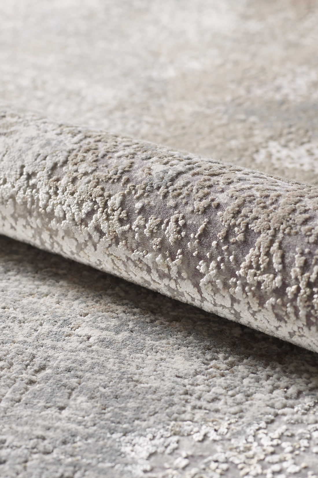 A close-up of the Chromatic Flair Contemporary Rug - Latte - M660D reveals its soft, uneven surface in beige and gray tones with a subtle pattern.
