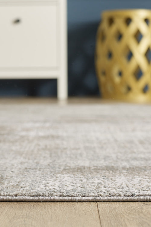 Load image 1 in gallery view. A close-up of the Chromatic Flair Contemporary Rug - Latte - M660D highlights its rich texture on a wooden floor, with a white cabinet and a decorative gold stool in the background.