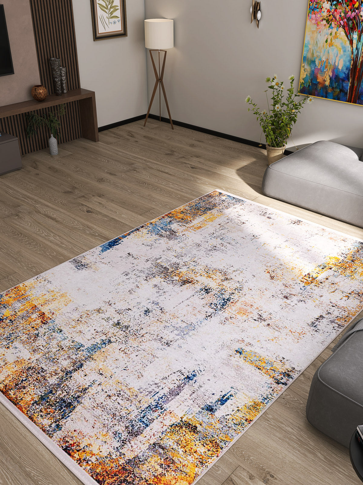 A modern living room with light wooden floors, abstract wall art, a floor lamp, and the Chromatic Kaleidoscope - Washable Rug - JR1483 (Custom Size), featuring a multicolored abstract pattern—perfect for high-traffic areas.