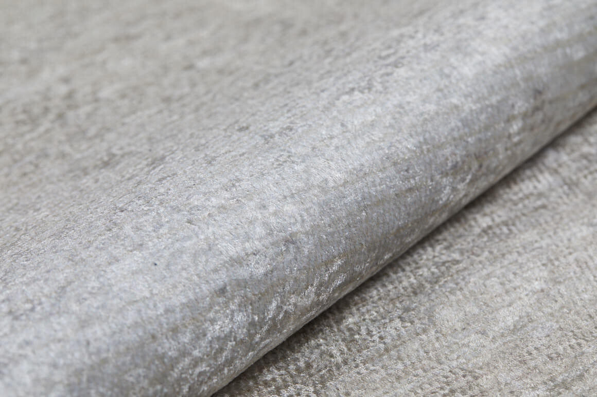 A close-up of the Cinnamon Swirl - Washable Rug - JR425 (Custom Size), showing its light gray, textured surface with a subtle metallic sheen—perfect for flat weaves or coordinating with cream and beige rugs.