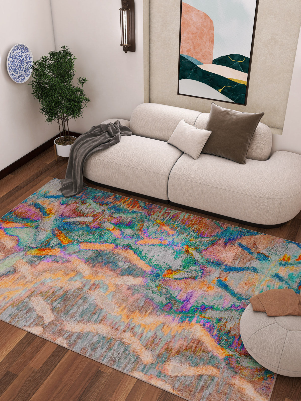 A modern living room with a cream sofa, brown and white pillows, gray throw blanket, round ottoman, potted plant, wall art, and the Classic Motif - Washable Rug - JRN29 with geometric patterns—ideal for high-traffic wooden floors.