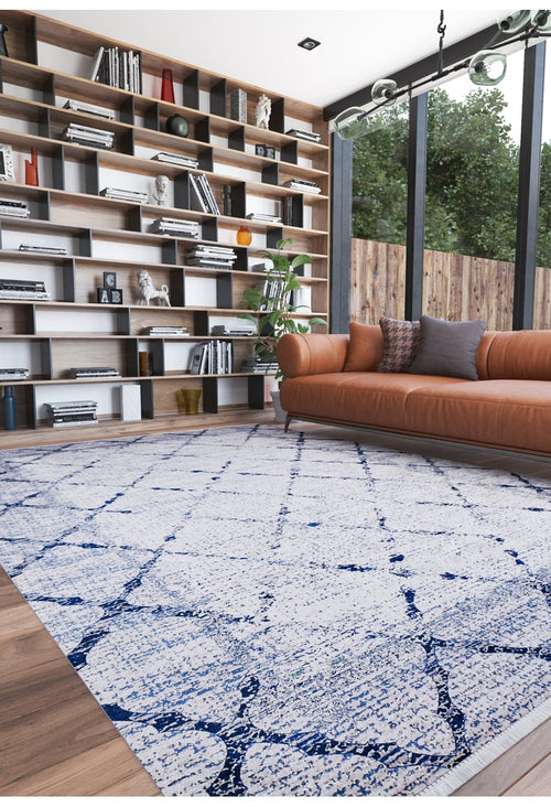 Load image 1 in gallery view. A modern living room features a brown leather sofa with cushions, a tall bookshelf, and the Classic Trellis - Washable Rug - JR710 (Custom Size) on a wooden floor. Large windows reveal trees outside.