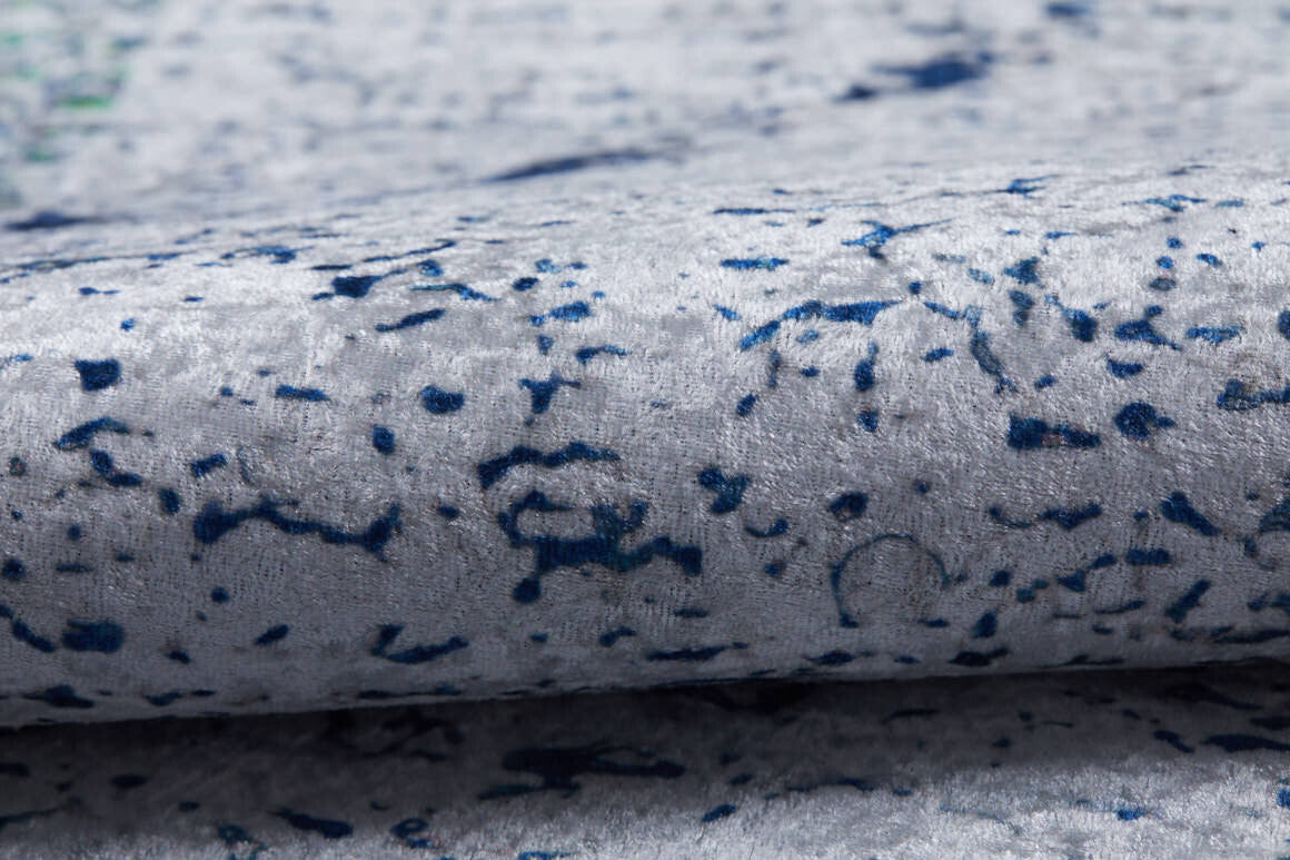 Close-up of the Classic Trellis - Washable Rug - JR710 (Custom Size) in light gray velvety fabric with dark blue speckles and lines. Its plush, gently folded surface is stylish, comfortable, and perfect for allergy-friendly living spaces.