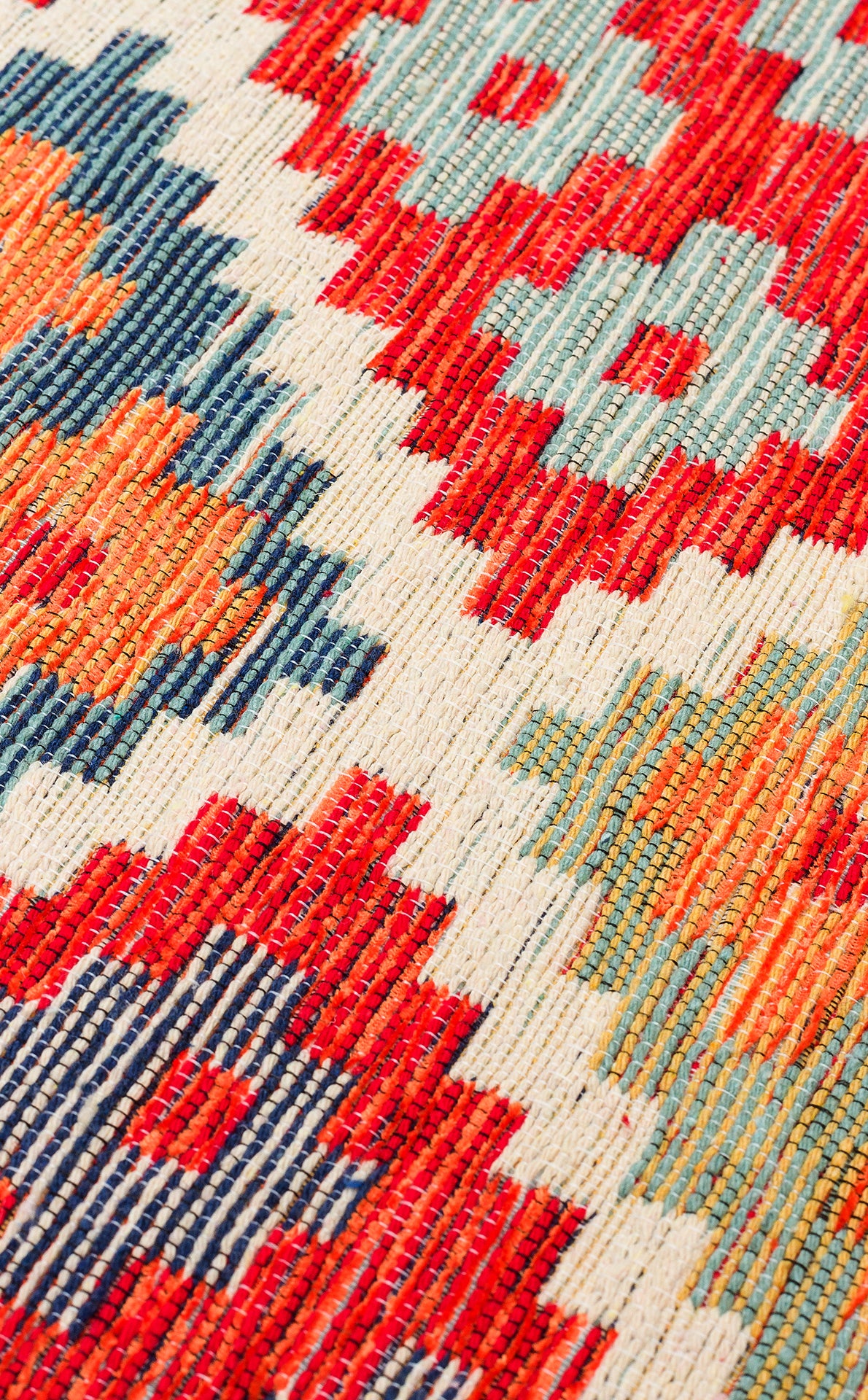 A close-up of the Clay Mark - Kilim - NMD05 rug highlights its handcrafted, flat-weave design with traditional folk-art geometric patterns in red, orange, blue, and cream featuring repeating diamonds and zigzags.