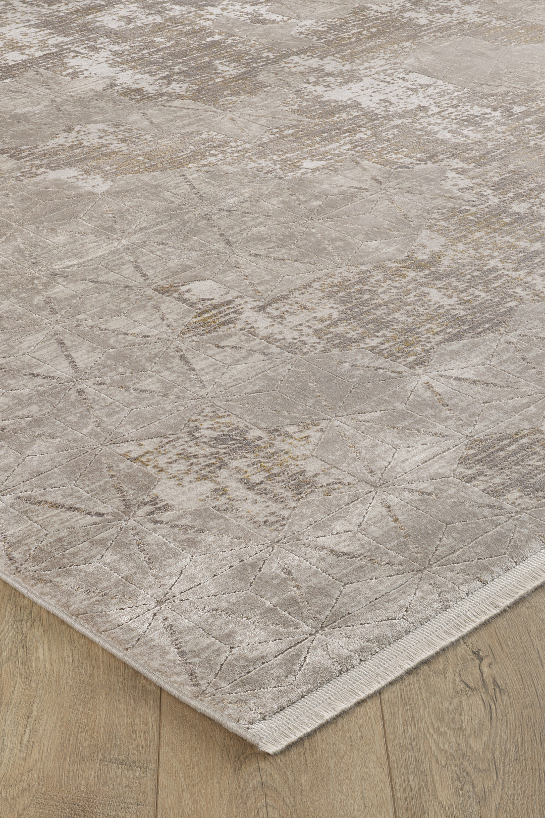 A close-up of the Cloudscape Geometry Modern Rug - M533B in beige and light brown on a light wood floor, highlighting its subtle geometric patterns, textured details, and stylish machine-made finish near the edge.