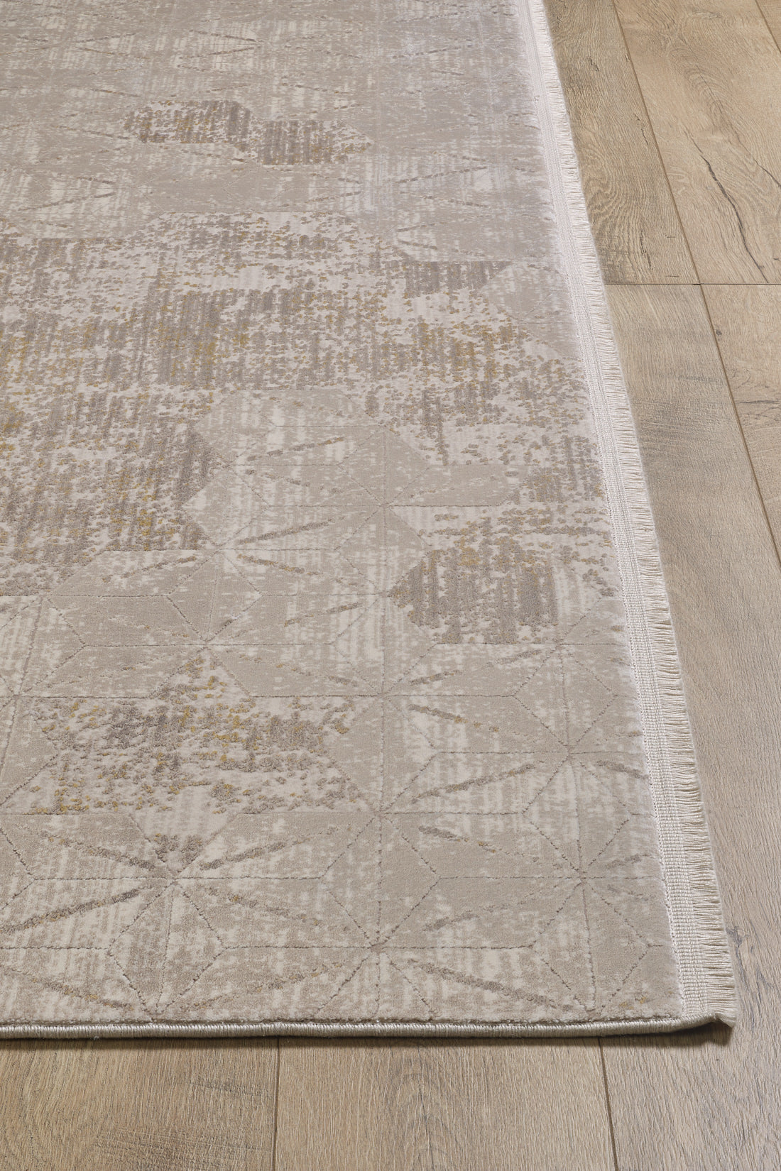 The Cloudscape Geometry Modern Rug - M533B, in beige and light brown with subtle geometric and abstract details and fringed edges on one side, is displayed on a wooden floor.