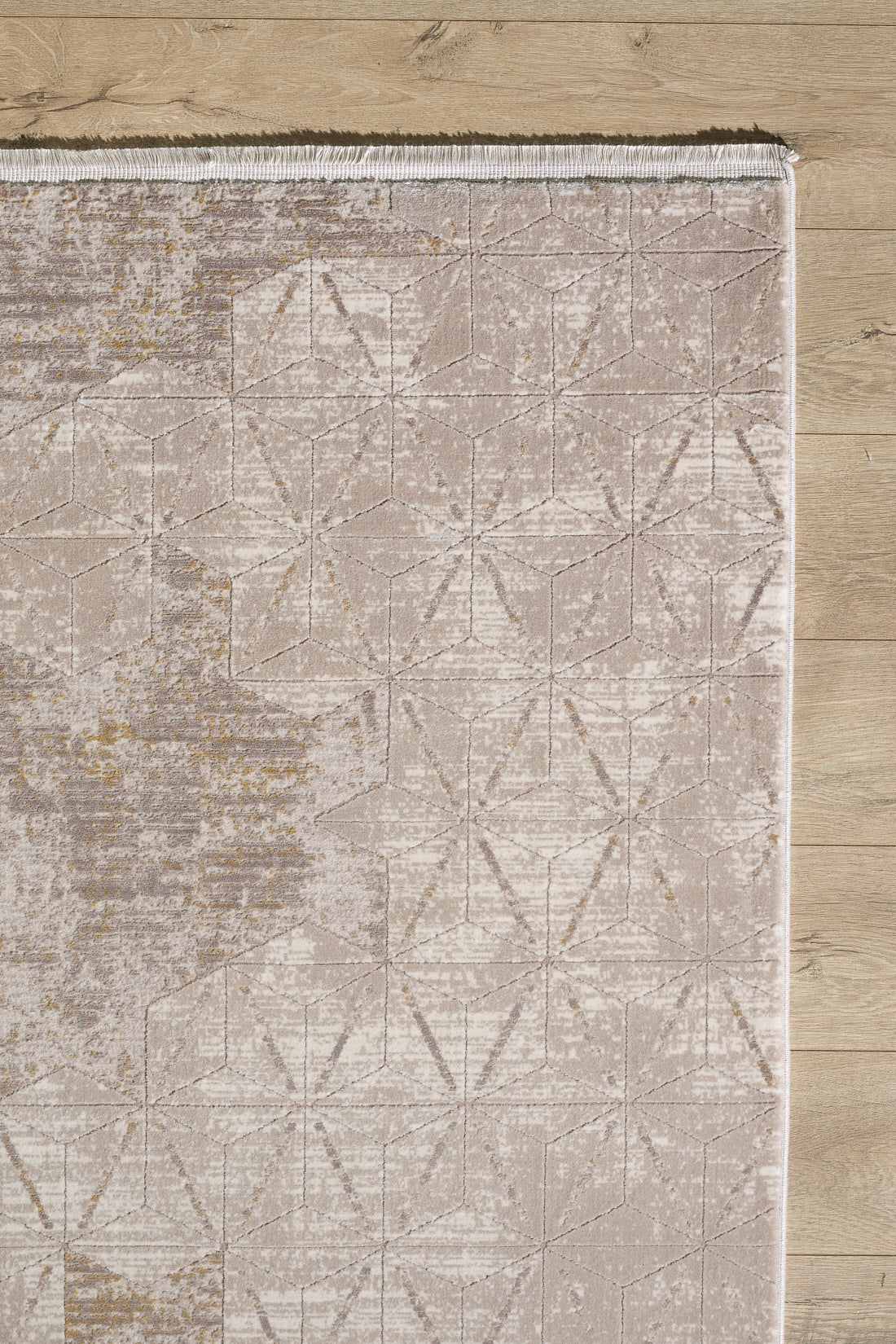 The Cloudscape Geometry Modern Rug - M533B features a beige and light brown geometric pattern with a subtle design. Shown here on a light wood floor, only the upper left section is visible, displaying tasseled edges at the top.