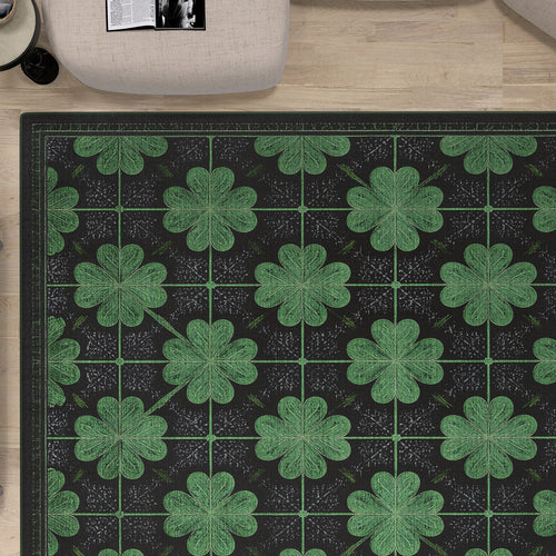 Load image 1 in gallery view. The Clover Noir - Washable Rug - JRS012 (Custom Size) features a black base with green four-leaf clovers, shown on a light wood floor. In the top left corner, part of a beige chair and an open magazine can be seen. Perfect for high-traffic areas.