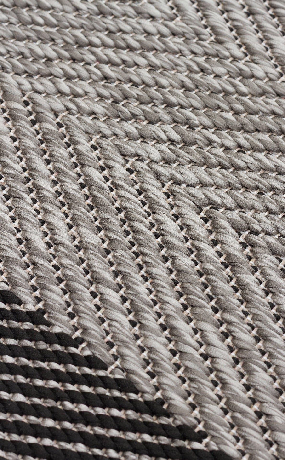 Close-up of Coal Texture - Kilim - MNO02, a woven textile with tightly interlaced fibers and diagonal gray and black zigzag lines, showcasing intricate craftsmanship and a flat weave rug-inspired design.