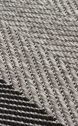 Close-up of Coal Texture - Kilim - MNO02, a woven textile with tightly interlaced fibers and diagonal gray and black zigzag lines, showcasing intricate craftsmanship and a flat weave rug-inspired design.