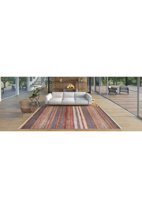 Load image 1 in gallery view. A modern living room features a white sofa, fireplace in a wooden wall, floor-to-ceiling windows, and the Coastal Breeze - Washable Rug - JR1549 (Custom Size)—perfect for high-traffic areas. A wicker chair sits on light wood floors with greenery outside.