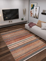 A modern living room with a Coastal Breeze - Washable Rug - JR1549 (Custom Size) on dark wood floors, a beige sectional sofa with cushions and a throw, abstract wall art, a wall-mounted TV, and minimalist décor with plants and vases.