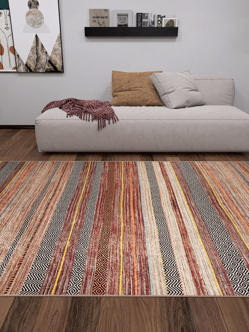 Load image 1 in gallery view. A modern living room features a beige sofa, tan pillow, red patterned throw, and the allergy-friendly Coastal Breeze - Washable Rug - JR1549 (Custom Size) in earthy tones—ideal for comfort and style. Wooden floor, wall art, and black shelf display books and decor.